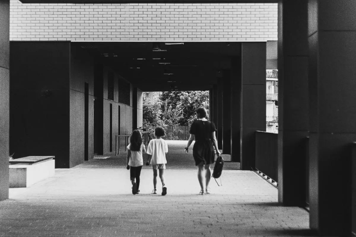 a woman and two girls walking down a walkway